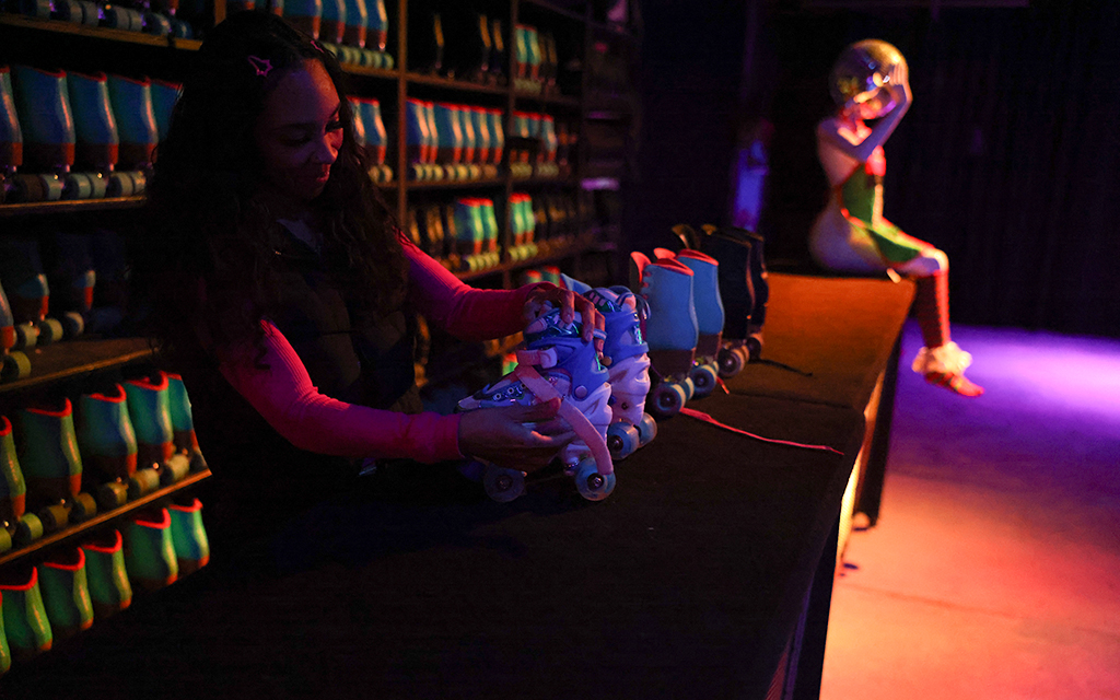 Ashley Madison, an employee at Zoni Girls in Phoenix cleans the inside of skates with disinfectant spray during a break from checking in new skaters on Nov. 16, 2024. (Photo by Aryton Temcio/Cronkite News)