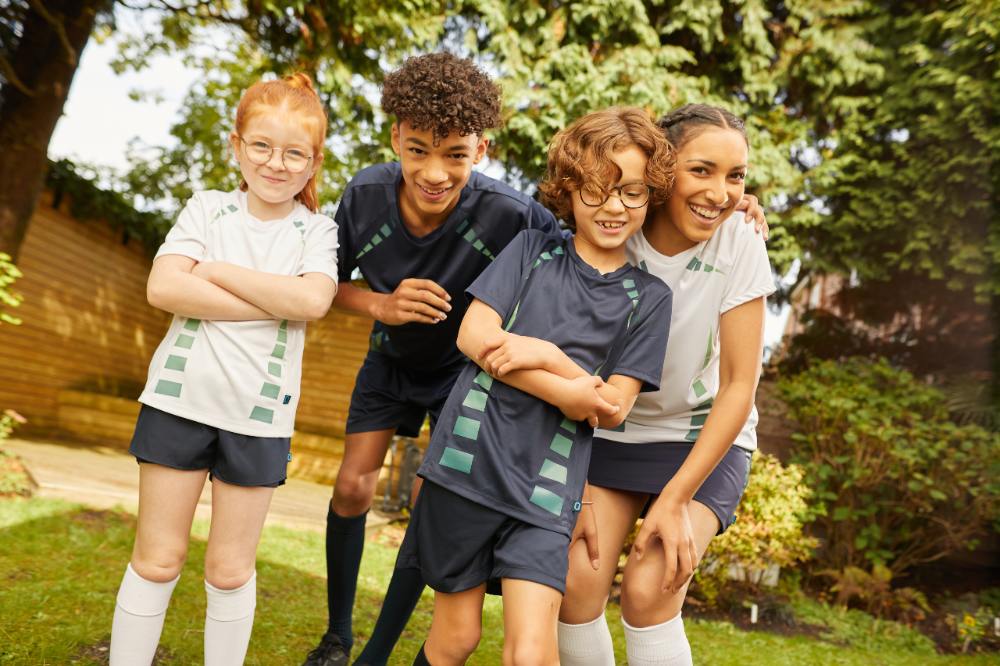 Four children stood outside in a garden wearing JUCO activewear