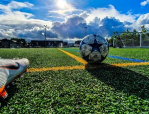 A football on a pitch with a football boot beside it