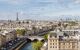 Aerial view of a bridge in Paris with the Eiffel Tower peeking through the city on a cloudy day