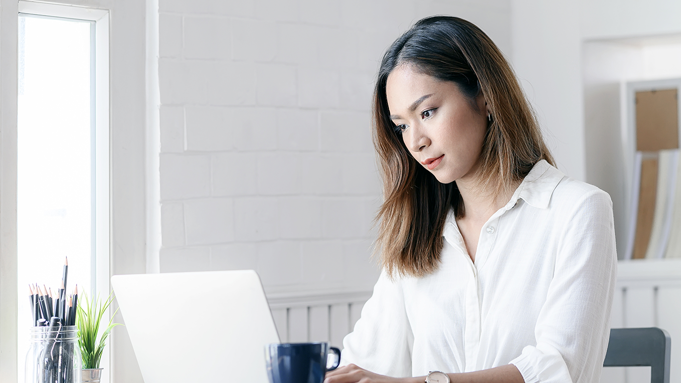 Woman sitting at desk with a laptop and learning how to develop cloud applications on AWS