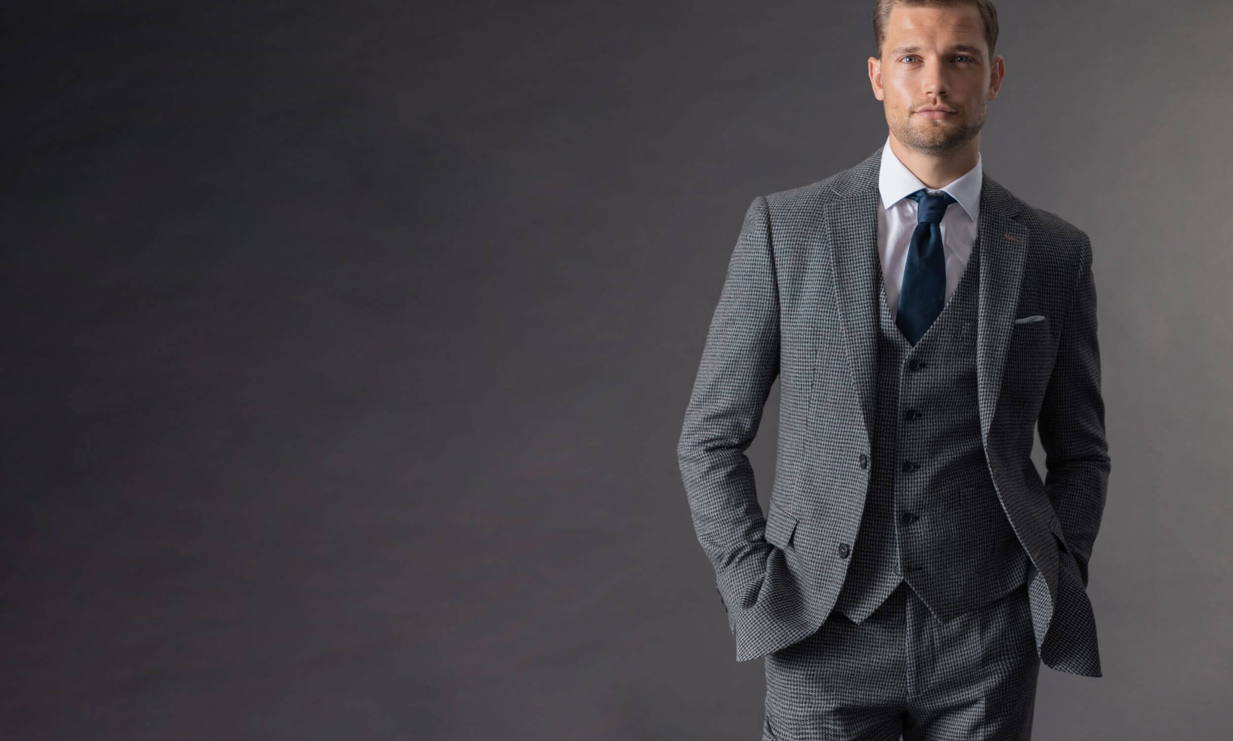 grey three piece suit with blue tie