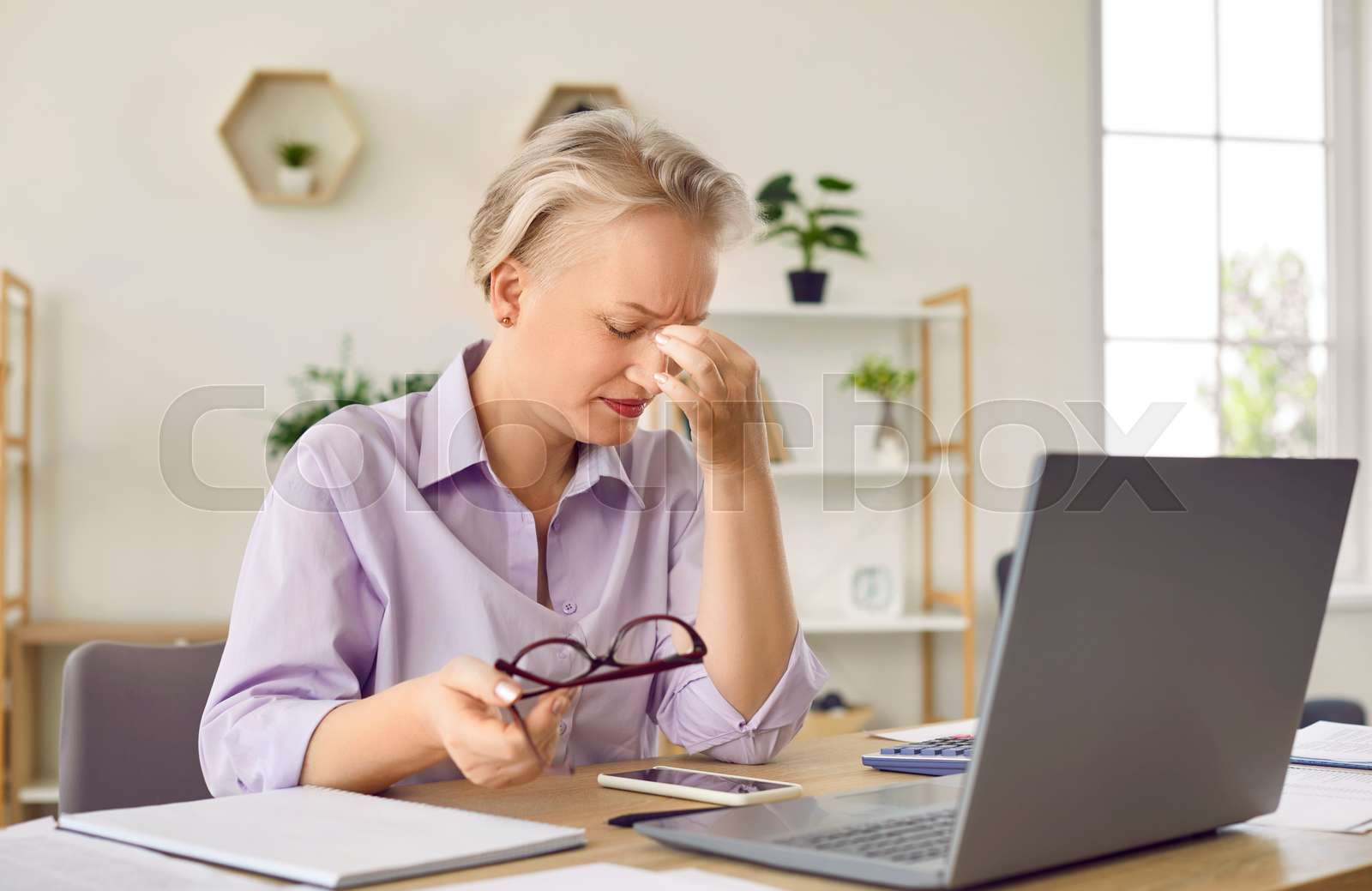 Tired senior business lady is overtired and has sore eyes from working on laptop in office.