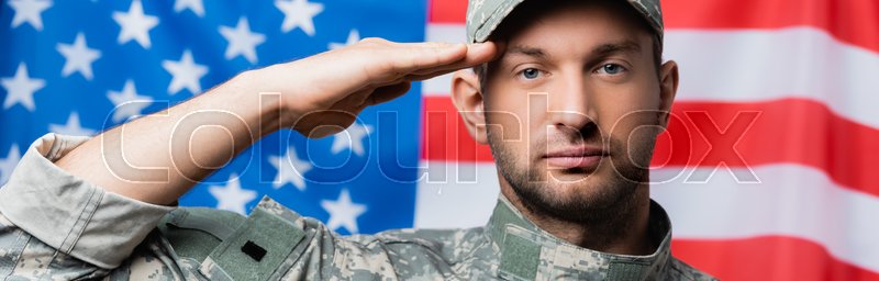 patriotic military man in uniform and cap giving salute near american flag  on blurred background, banner | Stock image | Colourbox