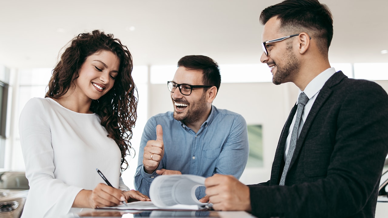 Middle age couple choosing and buying car at car showroom. Car salesman helps them to make right decision.