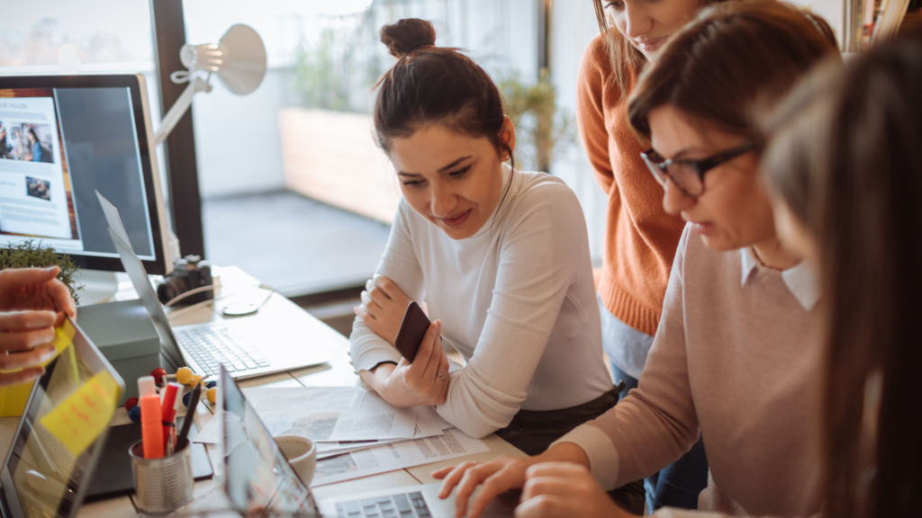 Female young entrepreneur sits with team at computer