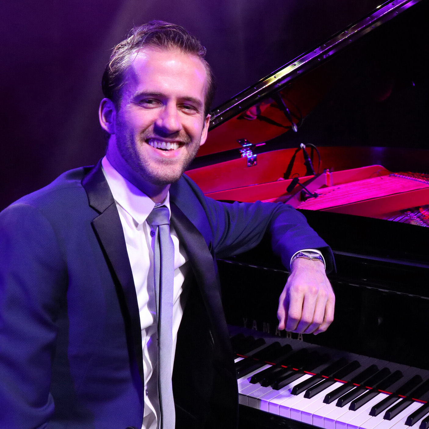 man in suit sitting at a piano