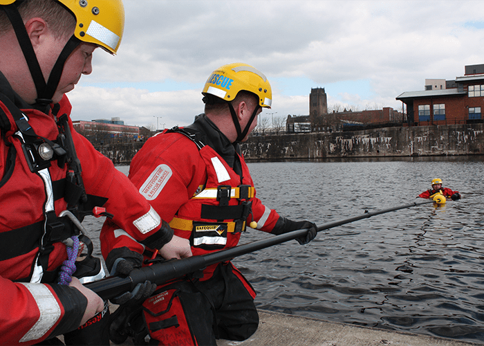 Person in the water being hauled to shore by a telescopic pole.