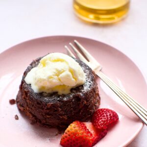 A decadent chocolate lava cake on a plate, served with fresh strawberries and topped with a scoop of vanilla ice cream, creating a delicious dessert presentation.