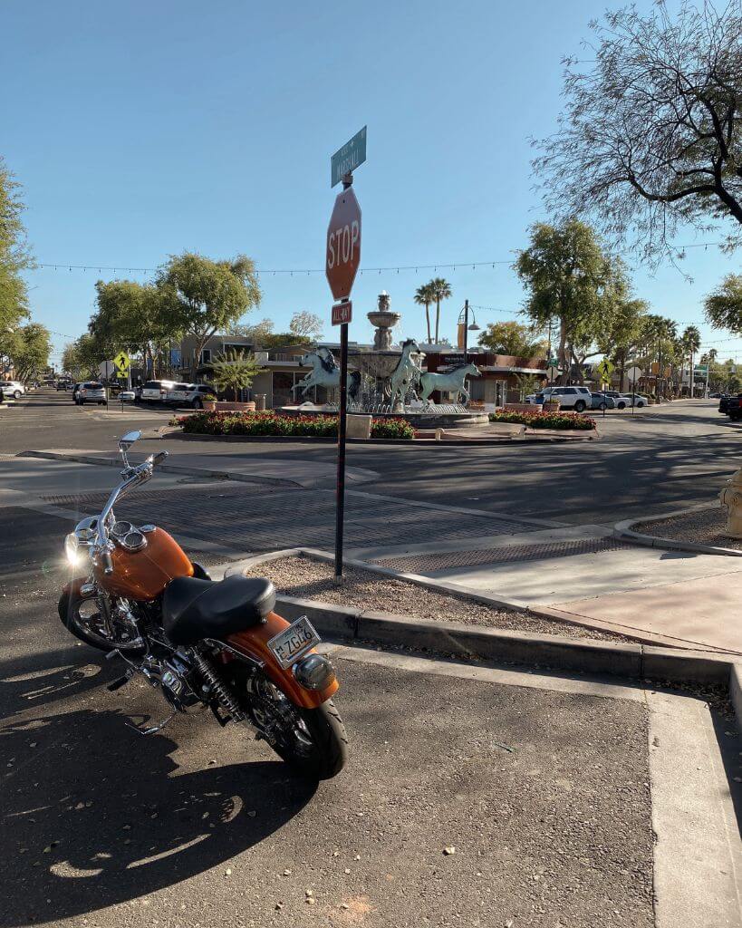 red motorcycle parked in front of a horse fountain in downtown scottsdale az