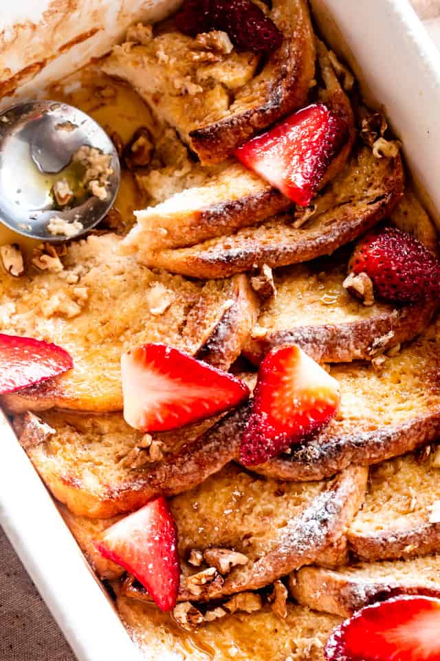 Baked French toast with sliced strawberries and maple syrup.