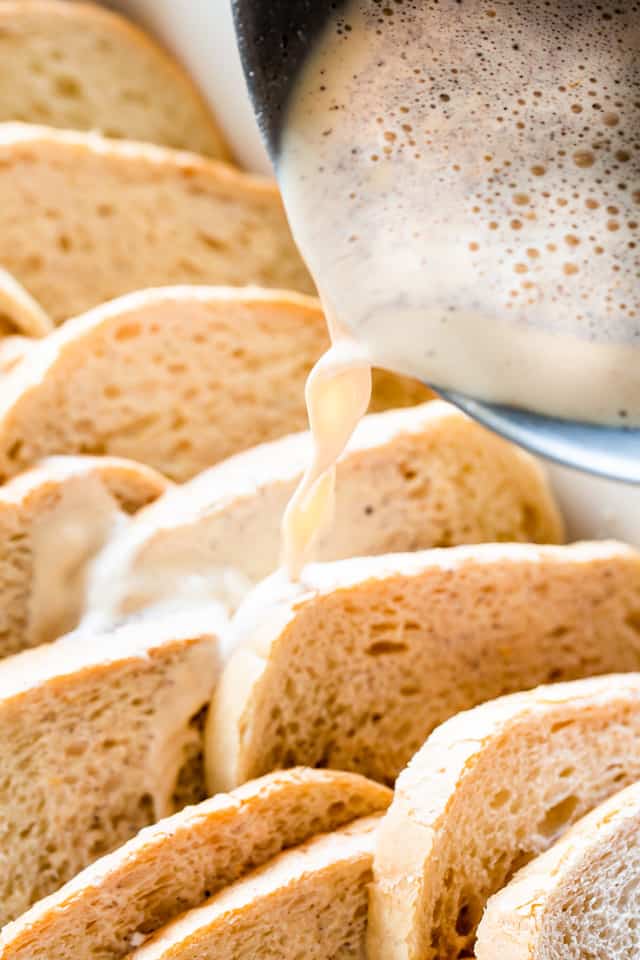 Pouring the custard over the bread slices in the baking dish. 