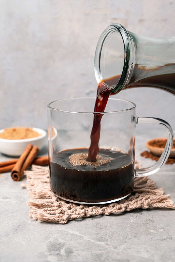 Pouring coffee into a glass mug with a handle.