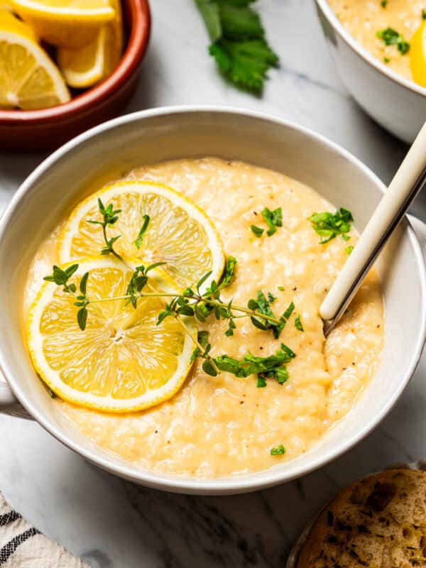 Lemon Rice Soup in a bowl with a garnish of lemon slices and green herbs.