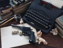 Writing a crime fiction book old retro vintage typewriter and revolver gun with ammunitions, books, papers, old ink pen