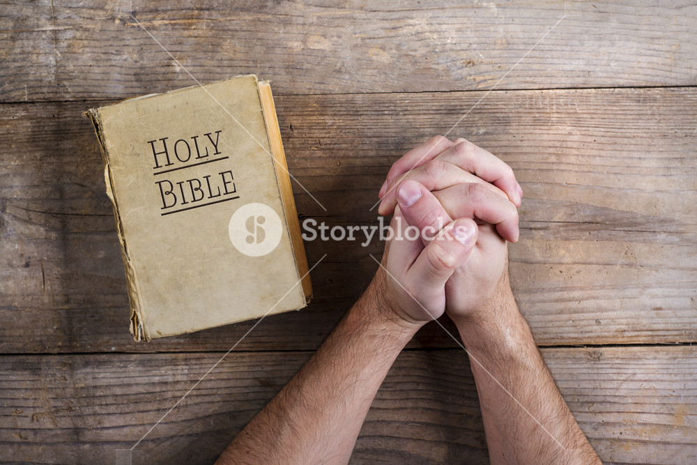 Hands of praying young man and Bible on a wooden desk background.  Royalty-Free Stock Image - Storyblocks