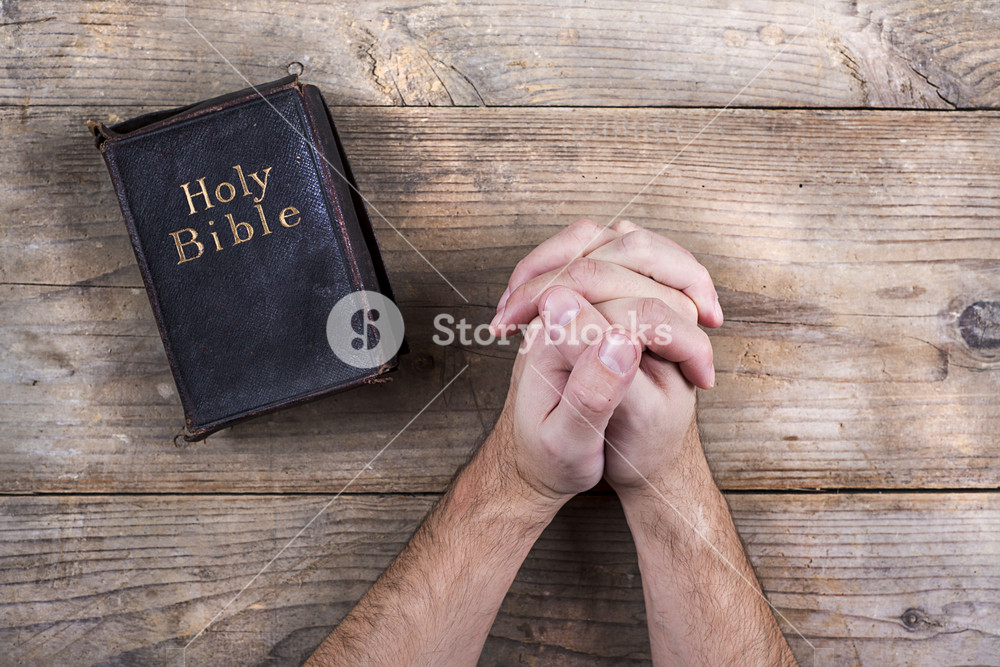 Hands of praying young man and Bible on a wooden desk background.  Royalty-Free Stock Image - Storyblocks