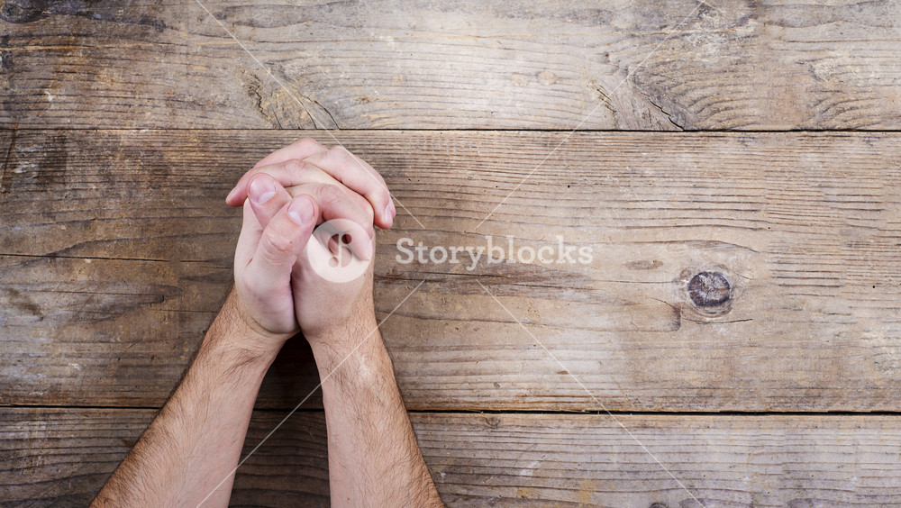 Hands of praying young man on a wooden desk background. Royalty-Free Stock  Image - Storyblocks