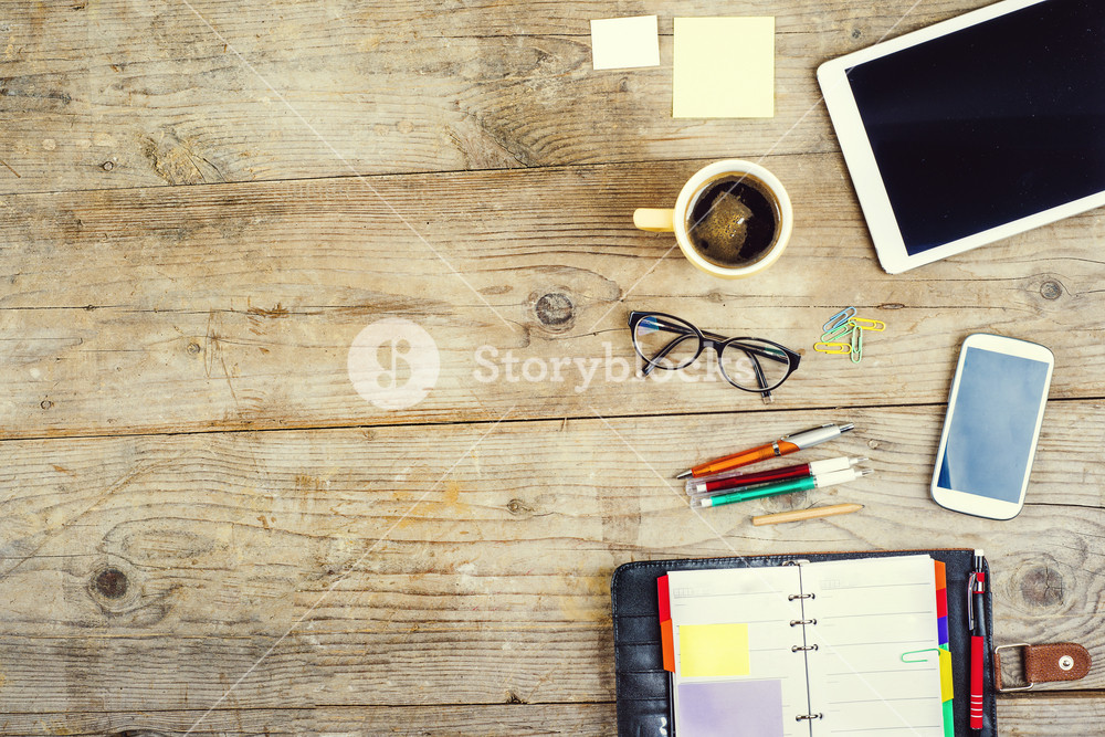 Mix of office supplies and gadgets on a wooden table background. View from  above. Royalty-Free Stock Image - Storyblocks