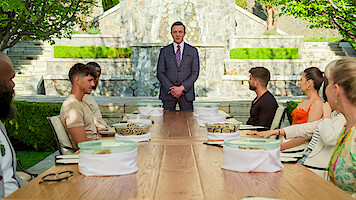 The cast of 'Million Dollar Secret' sitting at a table with snakes in front of them in containers.