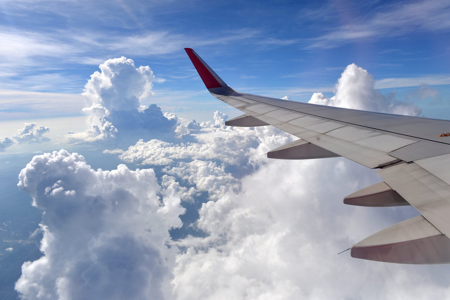 Wing of an airplane flying above the clouds on sky , look through the window, using air transport to travel. Dorset Airports Guide