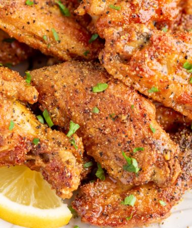 lemon pepper wings on a plate with a slice of lemon