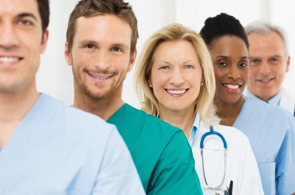 Five smiling doctors stand in a line.