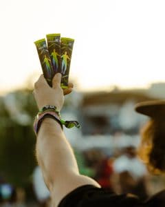 A person holding up three packs of marijuana.