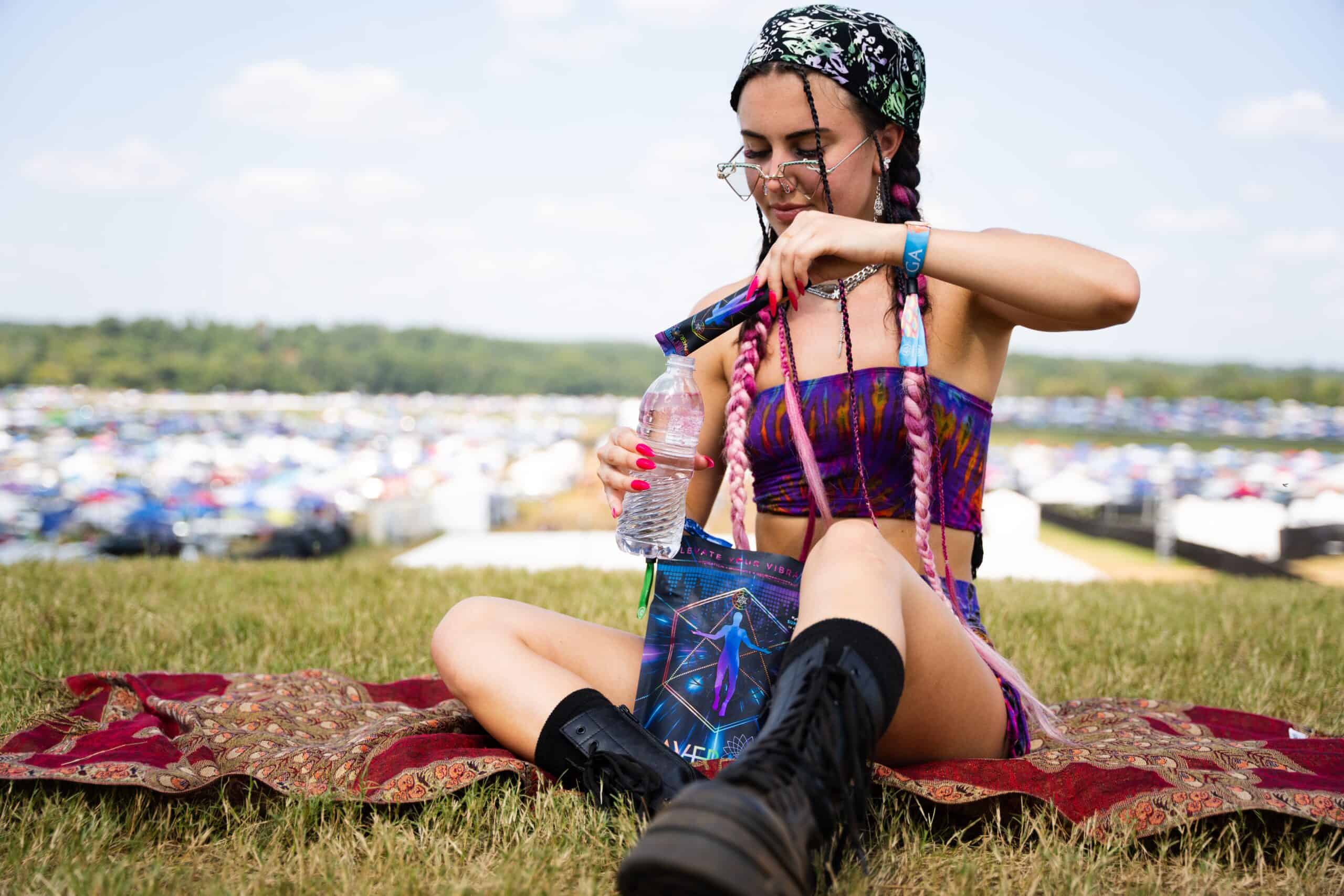 A woman sitting on the grass with her hands in her hair.