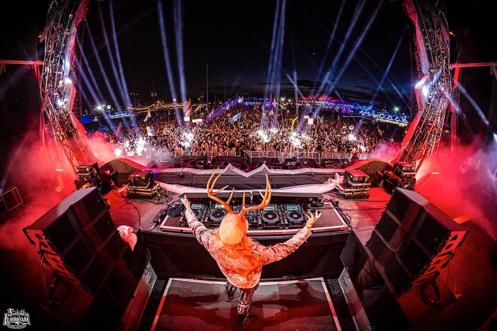 A man with antlers standing in front of a dj booth.