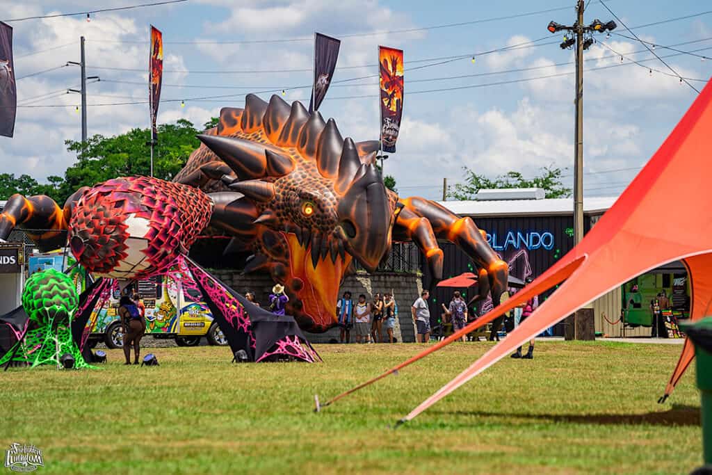 A dragon kite being flown in the grass.