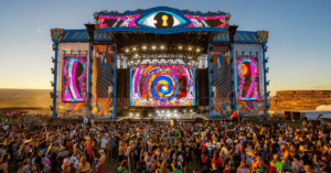 A crowd of people standing in front of an outdoor stage.