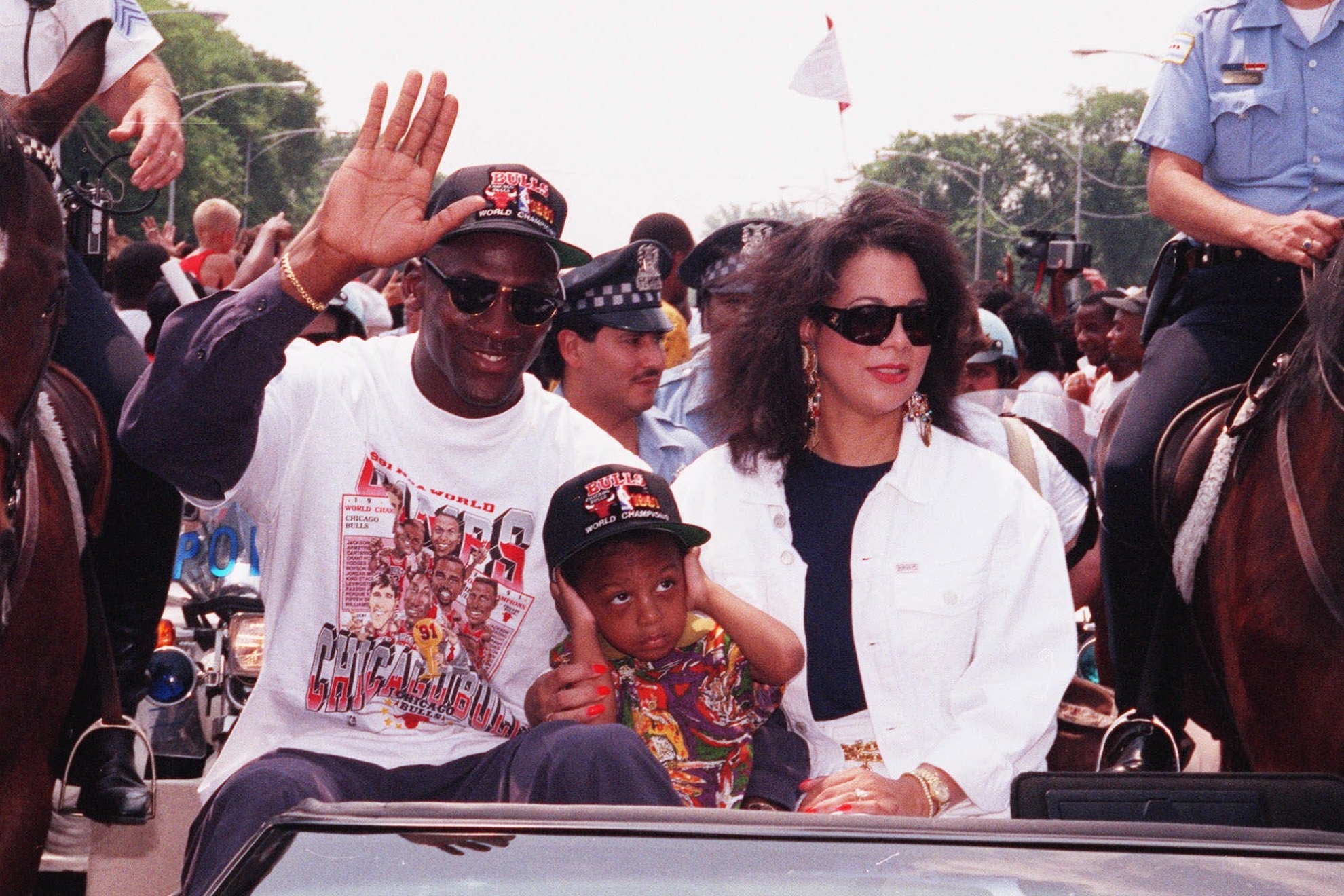 Chicago Bulls Michael Jordan waves to the crowd as he arrives for a victory rally with his wife Juanita and son Jeffrey, in Grant Park in Chicago, June 14, 1991. The team had won the NBA title and Jordan was named MVP of the series.