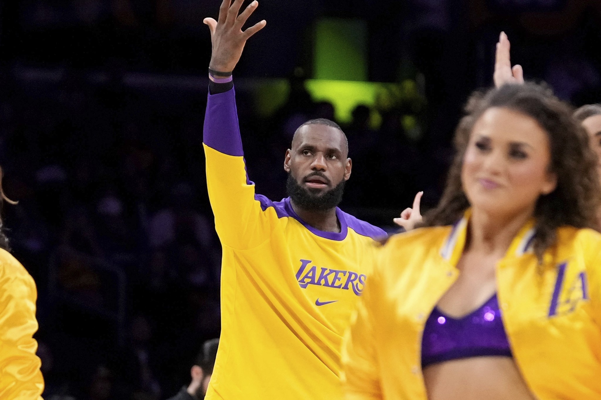 LeBron James, center, argues with a referee as members of the Laker Girls dance around him