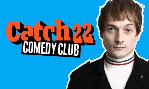 Comedian Matt Bragg, a young white man with short brown hair, stands alongside an orange Catch 22 Comedy Club logo.