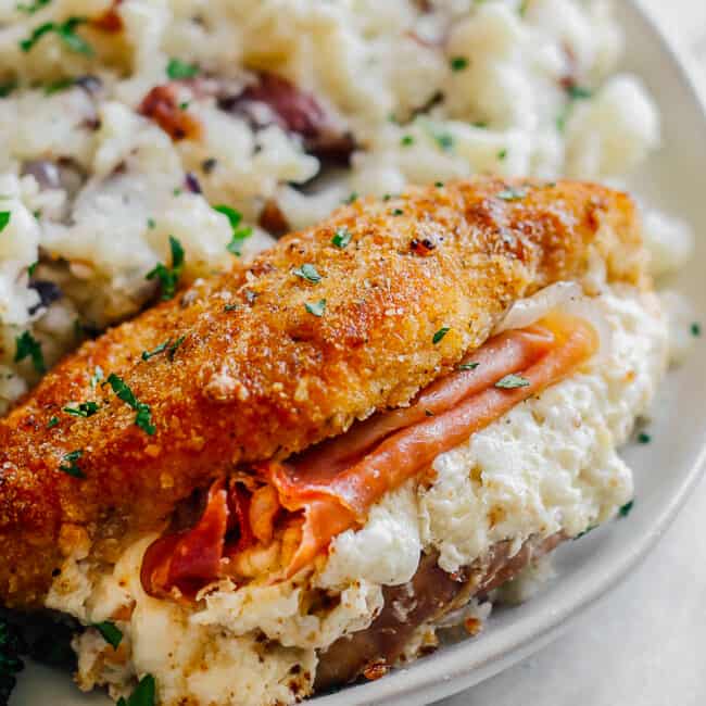 up close image of breaded chicken stuffed with prosciutto and cheese