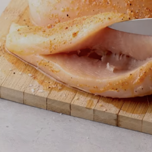 A raw chicken breast has been sliced to create a pocket.