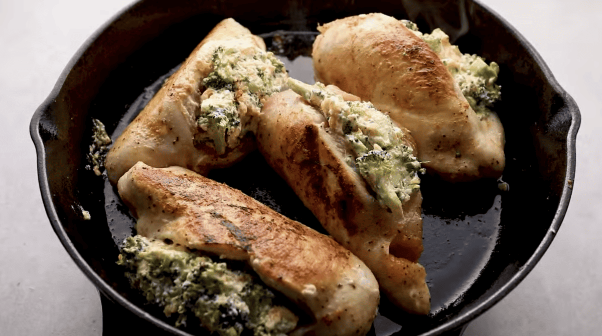 Stuffed chicken breasts are being seared in a pan.