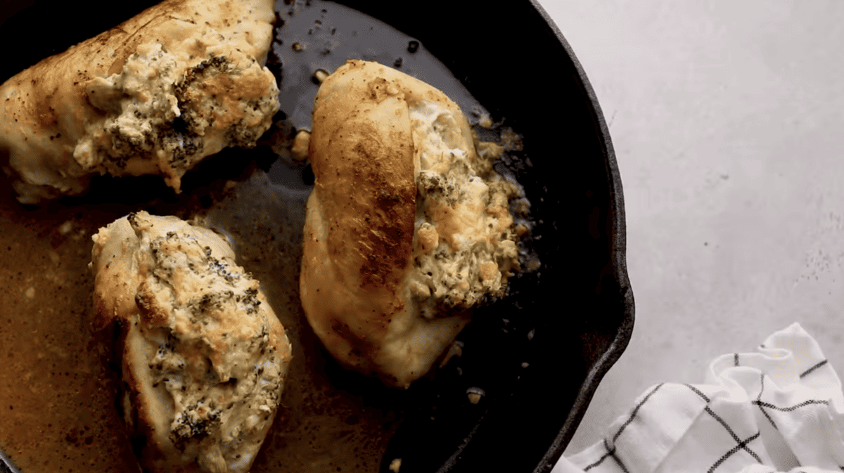 Broccoli and cheese stuffed chicken breasts in a cast iron skillet.