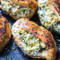 four broccoli and cheese stuffed chicken breasts cooked in a skillet.