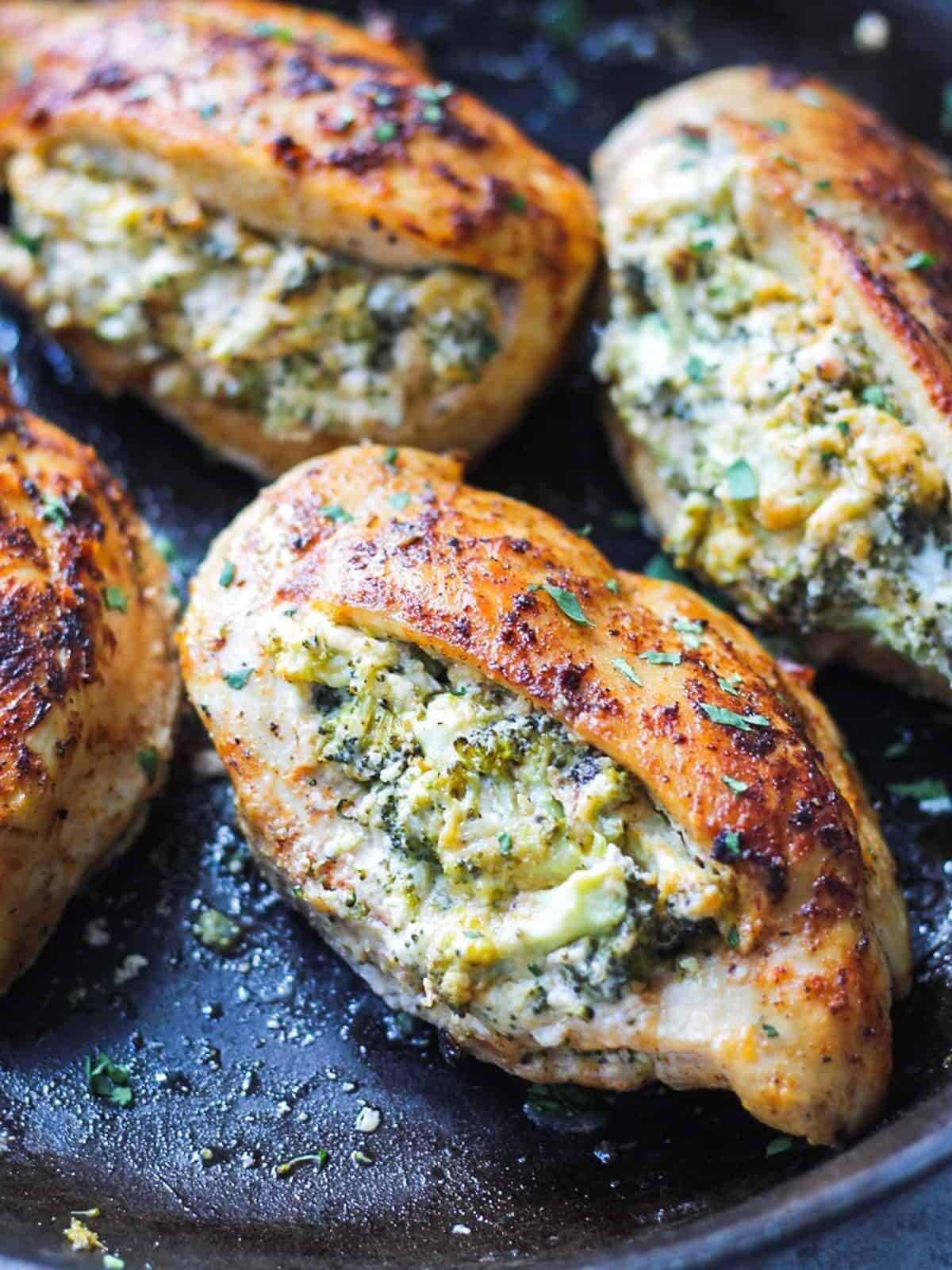 four broccoli and cheese stuffed chicken breasts cooked in a skillet.