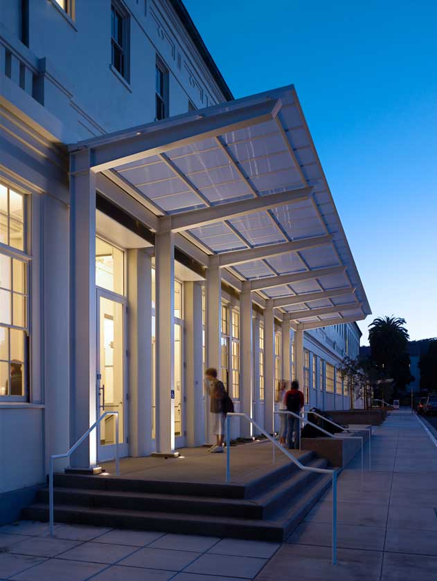 Exterior evening view of building with modern renovated entry overhang; interior lighting visible through large windows