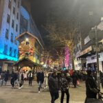 a crowd of people walking on a street with lights