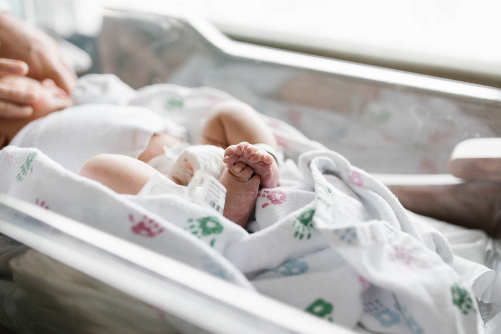 newborn baby's feet wrapped in a hospital swaddle blanket 