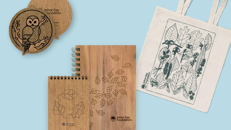 tote bag with line art of leaves, wooden covered notepads, and a wooden ornament with an owl