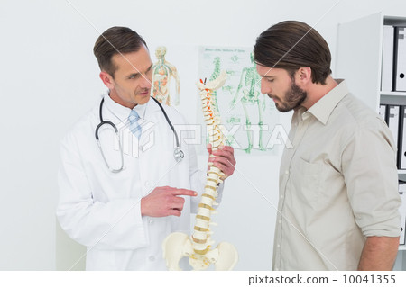 Stock Photo: Male doctor explaining the spine to a patient