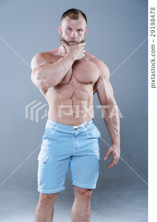 Brutal strong bodybuilder man posing in studio on grey backgroun 29198478