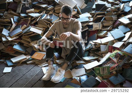 Young man sitting near scattered books 29715292