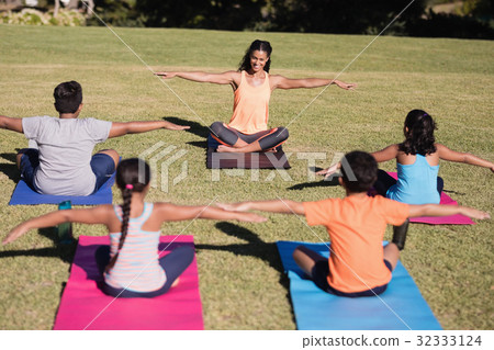 Happy trainer teaching stretching exercise to children 32333124