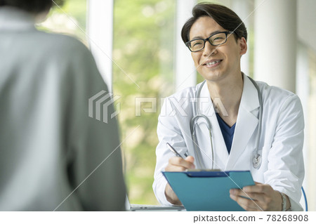 Male doctor examining with a smile 78268908